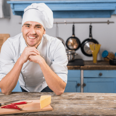 Smiling chef with food on chopping board in kitchen